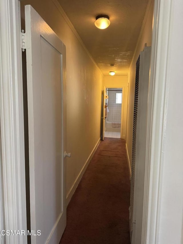 hall featuring dark colored carpet and ornamental molding