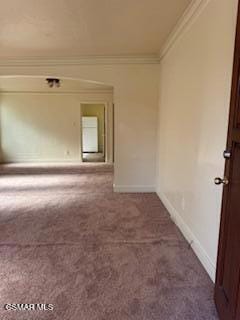 empty room with ornamental molding and dark carpet