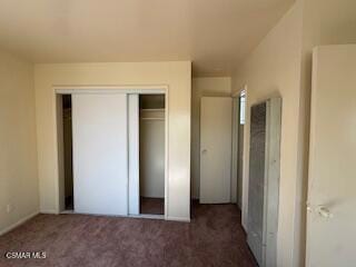 unfurnished bedroom with a closet and dark carpet