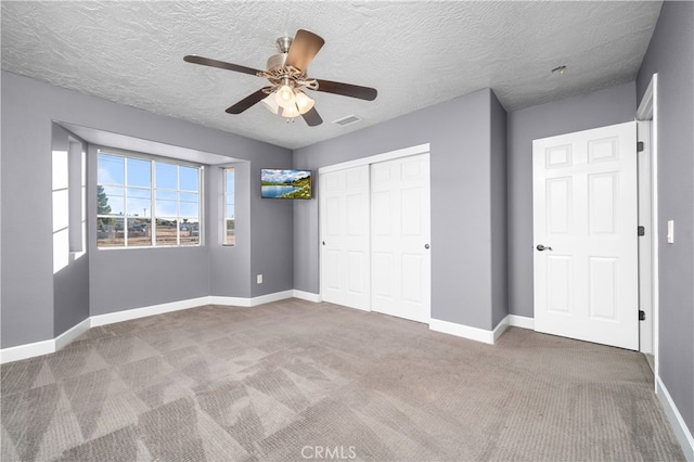 unfurnished bedroom with ceiling fan, a closet, a textured ceiling, and carpet flooring