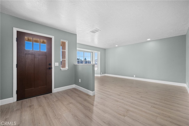 entrance foyer with a textured ceiling and light hardwood / wood-style flooring