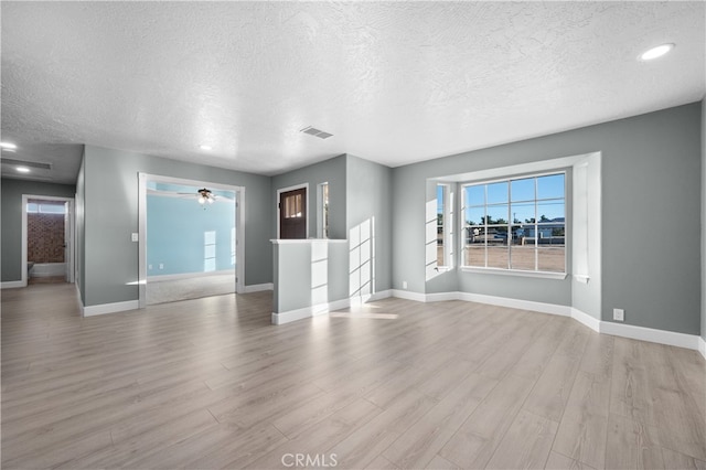 unfurnished living room featuring a textured ceiling, ceiling fan, and light hardwood / wood-style floors