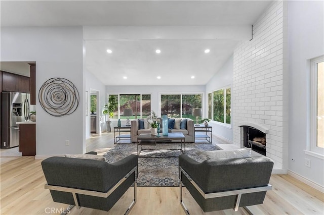 living room featuring light hardwood / wood-style floors, a brick fireplace, high vaulted ceiling, and beamed ceiling