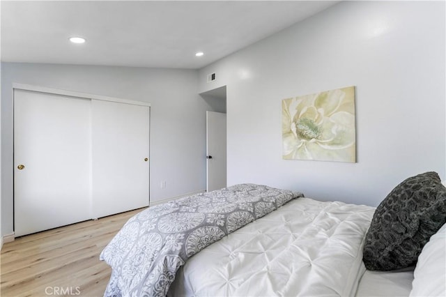 bedroom featuring a closet, vaulted ceiling, and light hardwood / wood-style flooring