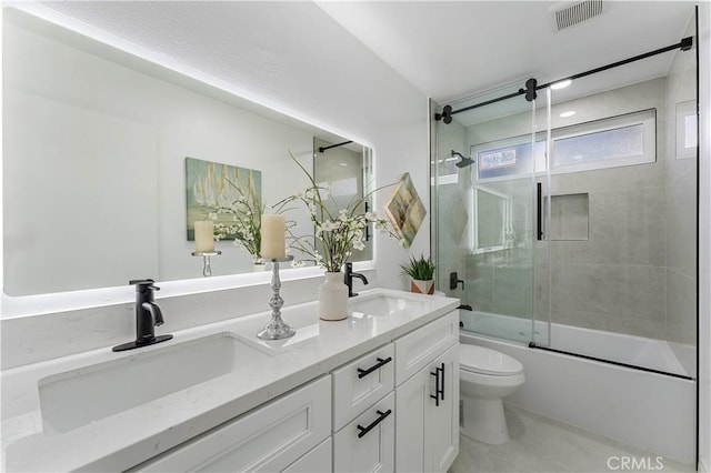 full bathroom featuring toilet, combined bath / shower with glass door, and vanity