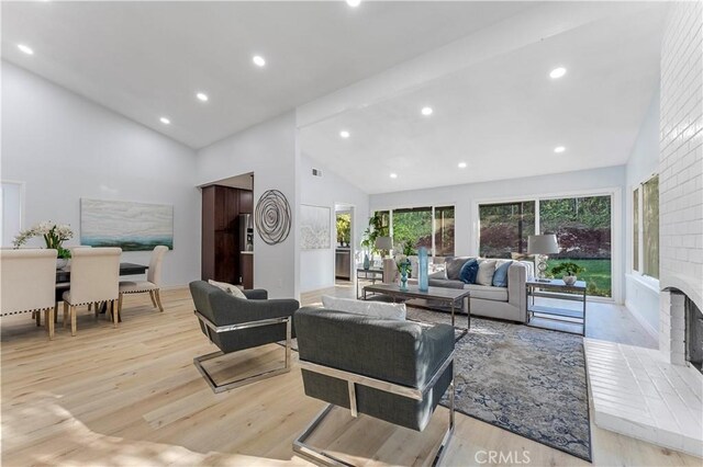 living room featuring a brick fireplace, high vaulted ceiling, and light hardwood / wood-style floors