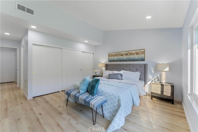 bedroom with lofted ceiling, light wood-type flooring, and a closet