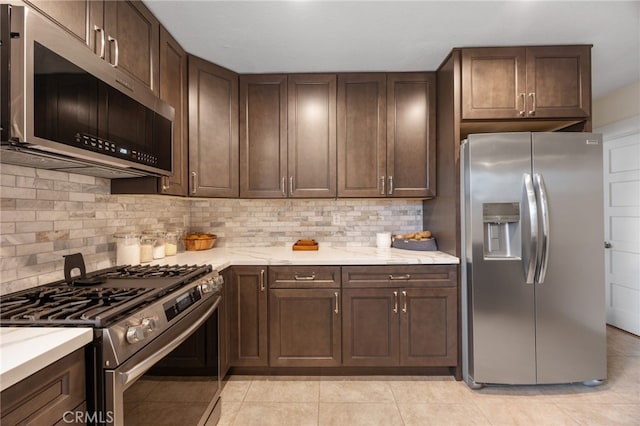 kitchen featuring light stone counters, stainless steel appliances, dark brown cabinets, and backsplash