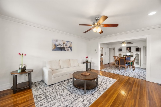 living room featuring ceiling fan, ornamental molding, and hardwood / wood-style flooring