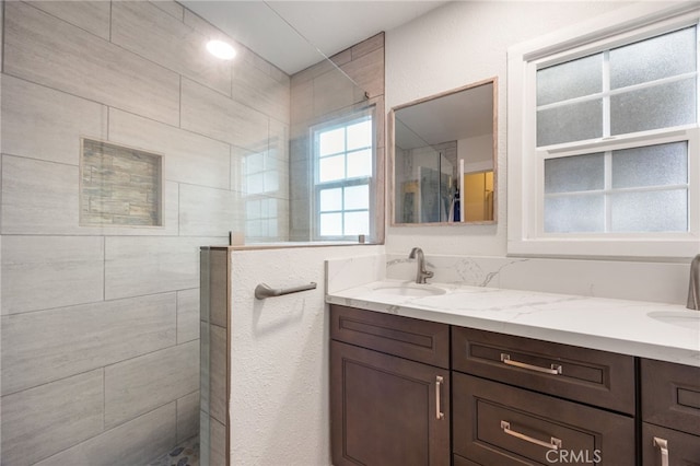 bathroom with a tile shower and vanity