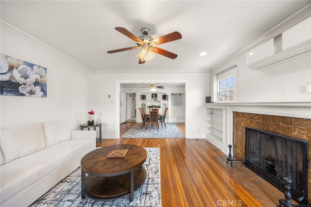 living room with ornamental molding, a wall mounted AC, a tile fireplace, and hardwood / wood-style flooring