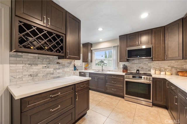 kitchen with appliances with stainless steel finishes, backsplash, sink, and dark brown cabinetry