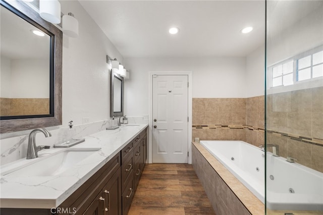 bathroom with tiled tub, vanity, and wood-type flooring