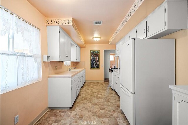 kitchen featuring white appliances, a healthy amount of sunlight, and white cabinets