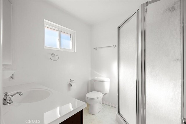 bathroom featuring a shower with door, vanity, and toilet