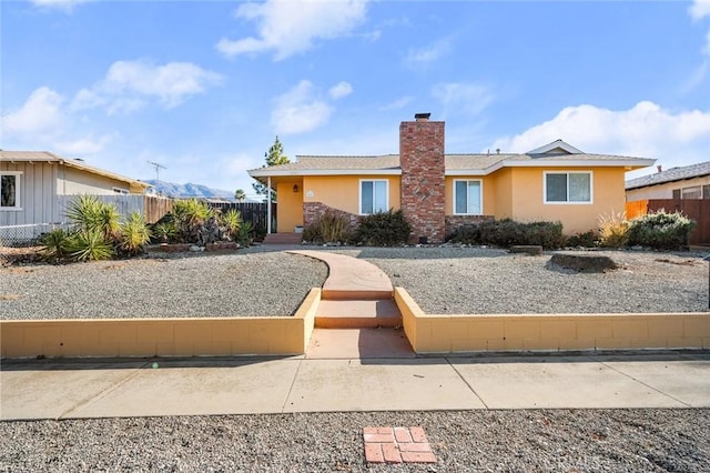 view of front of house featuring fence, a chimney, and stucco siding