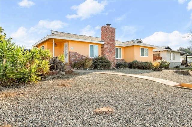 rear view of house with a chimney and stucco siding