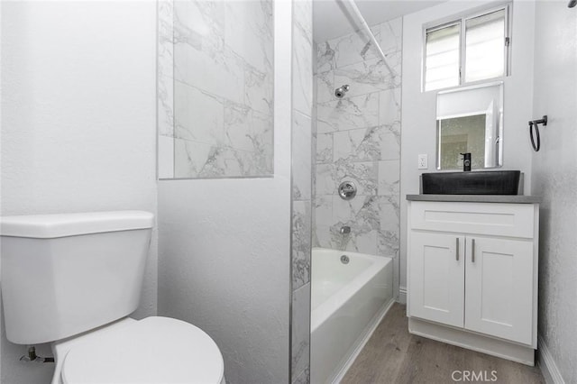 full bathroom featuring toilet, tiled shower / bath combo, wood-type flooring, and vanity