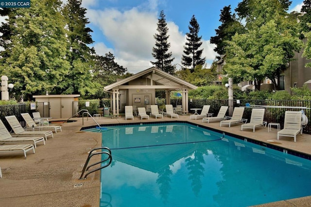 view of pool featuring a storage unit and a patio