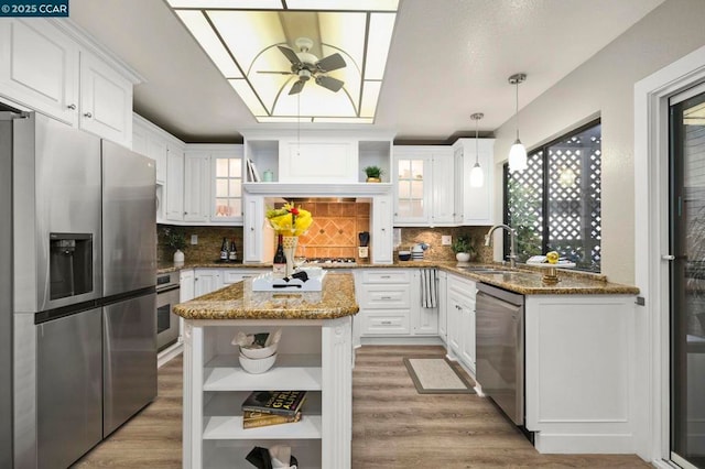 kitchen featuring sink, appliances with stainless steel finishes, light stone countertops, white cabinets, and decorative light fixtures