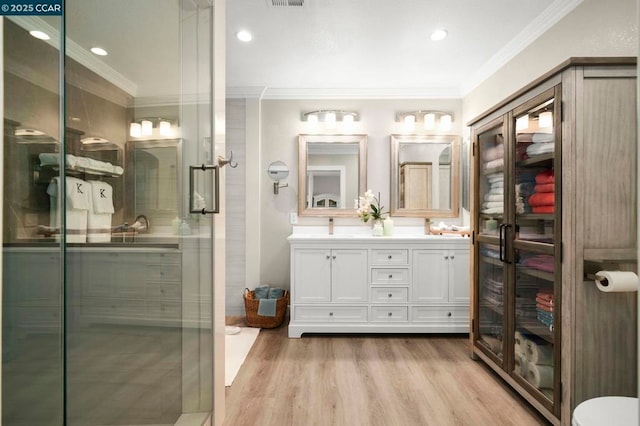 bathroom featuring vanity, ornamental molding, hardwood / wood-style floors, and a shower with shower door