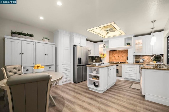 kitchen featuring pendant lighting, sink, white cabinetry, stainless steel appliances, and a center island