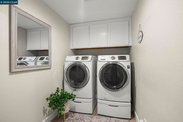 clothes washing area featuring cabinets and washing machine and dryer