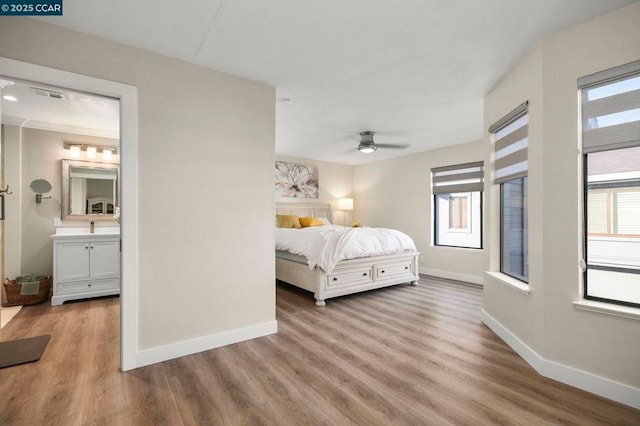 bedroom featuring ensuite bathroom, light hardwood / wood-style floors, and multiple windows