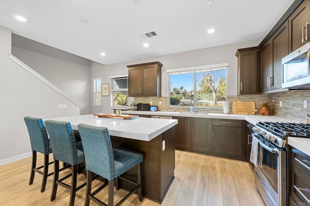 kitchen featuring appliances with stainless steel finishes, a center island, sink, and a breakfast bar area