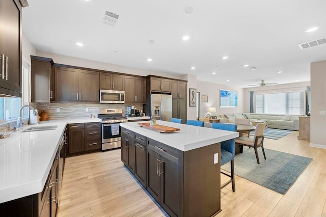 kitchen featuring appliances with stainless steel finishes, sink, a breakfast bar area, a center island, and ceiling fan