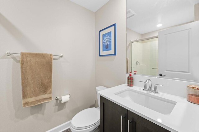 bathroom with a stall shower, vanity, toilet, and baseboards