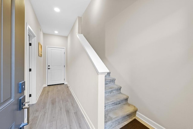 stairway featuring baseboards, wood finished floors, and recessed lighting