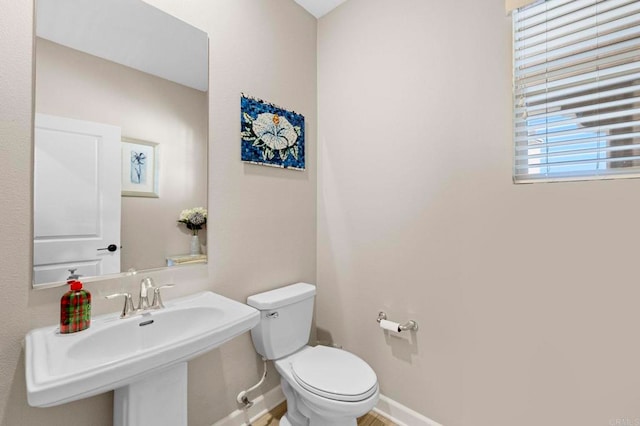 bathroom featuring a sink, toilet, and baseboards