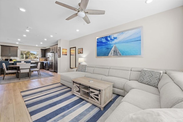 living area with light wood finished floors, a ceiling fan, and recessed lighting