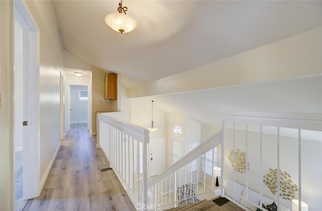 corridor with vaulted ceiling and light wood-type flooring