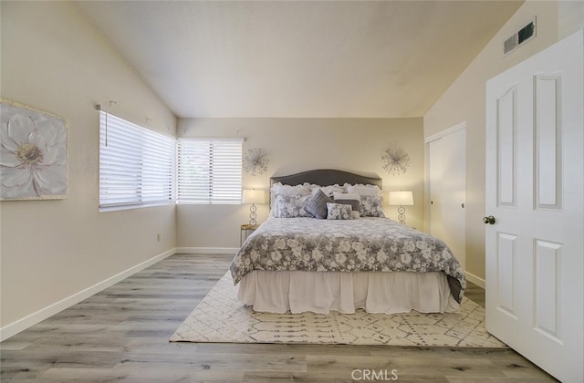 bedroom with wood-type flooring and vaulted ceiling