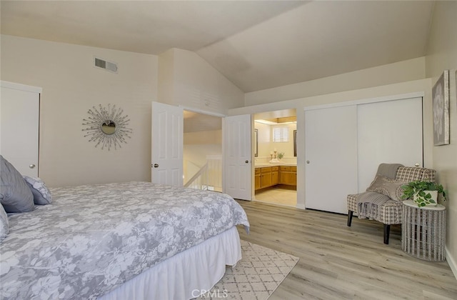 bedroom with a closet, ensuite bathroom, lofted ceiling, and light hardwood / wood-style flooring