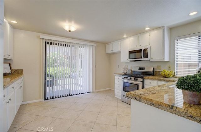 kitchen featuring light stone countertops, white cabinets, appliances with stainless steel finishes, and light tile patterned flooring