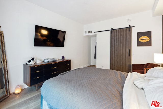 bedroom featuring a barn door and light wood-type flooring