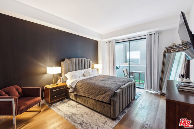 bedroom with access to exterior, dark hardwood / wood-style flooring, and multiple windows