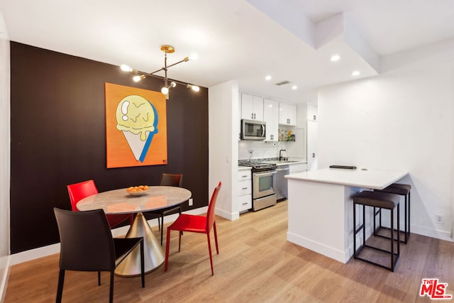 kitchen featuring a notable chandelier, decorative backsplash, hanging light fixtures, appliances with stainless steel finishes, and white cabinets