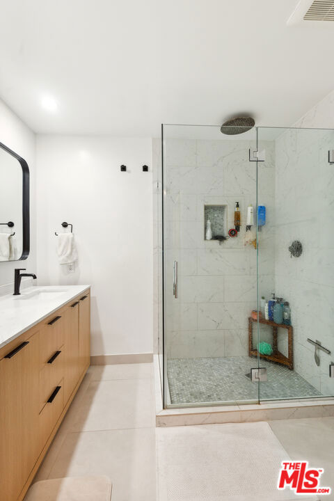 bathroom with tile patterned flooring, a shower with shower door, and vanity