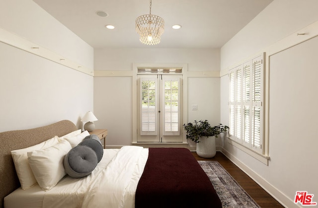 bedroom featuring an inviting chandelier, dark hardwood / wood-style floors, and access to outside