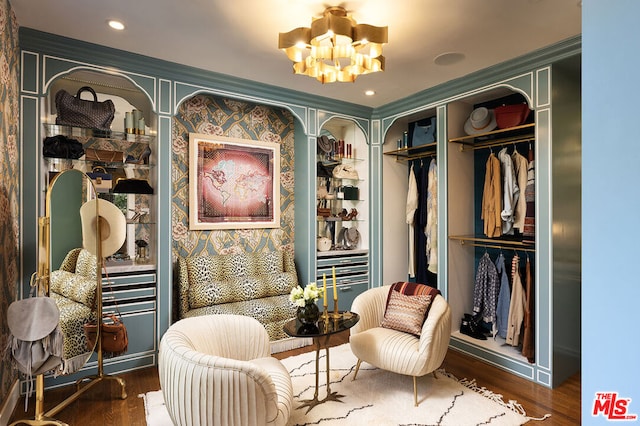 living area featuring crown molding, dark wood-type flooring, and a notable chandelier