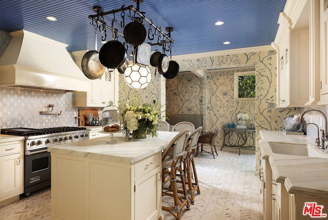 kitchen featuring sink, white cabinetry, premium stove, a kitchen island, and custom exhaust hood