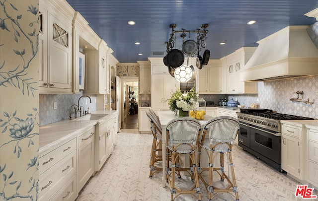 kitchen featuring a breakfast bar, tasteful backsplash, sink, double oven range, and custom range hood