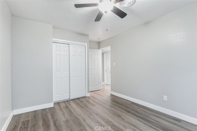 unfurnished bedroom with ceiling fan, a closet, and hardwood / wood-style flooring