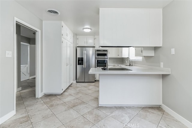 kitchen with kitchen peninsula, stainless steel appliances, white cabinetry, and sink