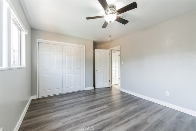 unfurnished bedroom featuring ceiling fan, a closet, and dark wood-type flooring