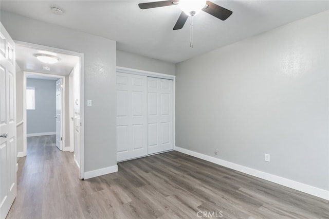 unfurnished bedroom featuring a closet, hardwood / wood-style flooring, and ceiling fan